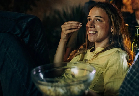 Woman enjoying a movie night with popcorn on the couch at JLT cinema.