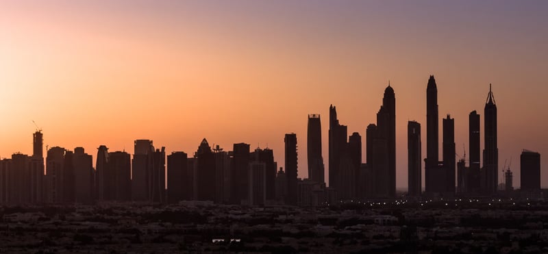 Dimly lit Dubai skyline during sunset.