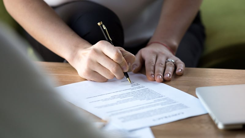 A person signing a contract with a pen